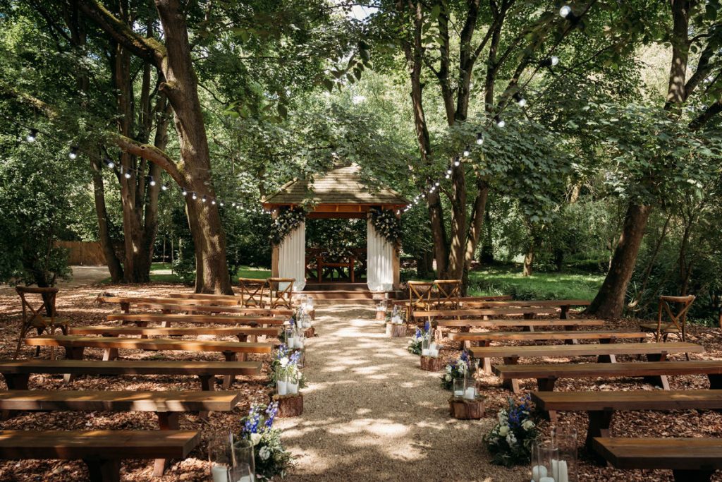 Outdoor woodland wedding ceremony with benches and altar.