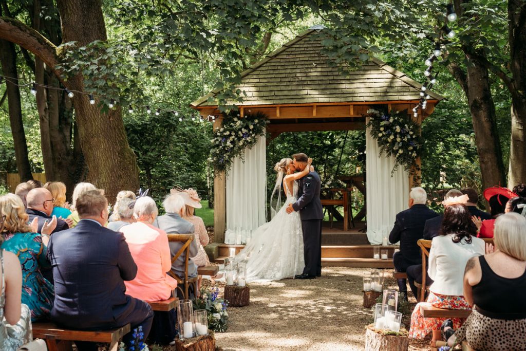 Outdoor wedding ceremony with kissing couple