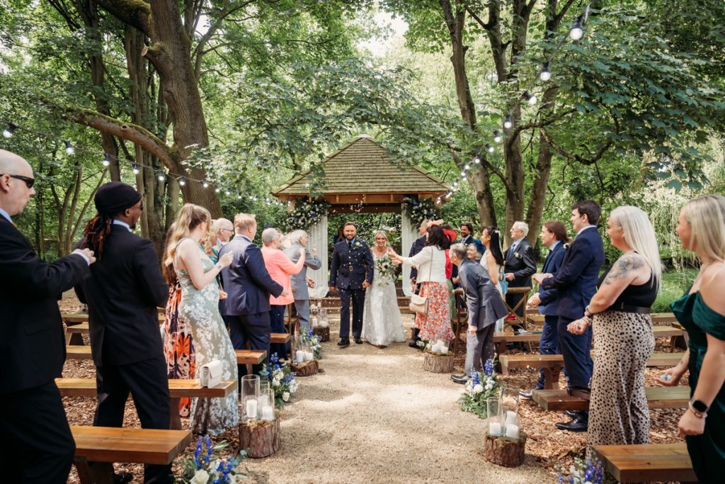 Outdoor wedding ceremony with guests applauding newlyweds.