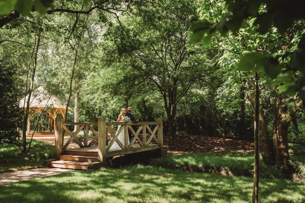 Bride and groom on bridge in lush garden
