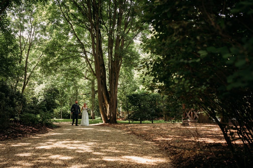 Couple walking in a sunlit forest pathway.