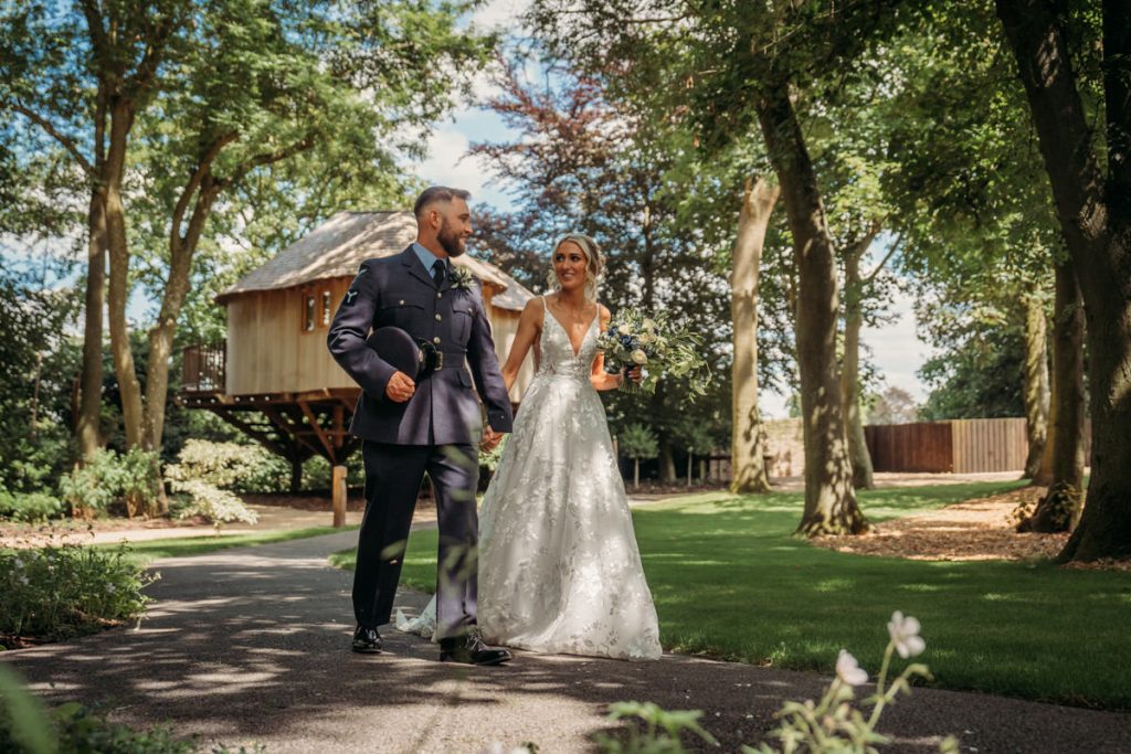 Bride and groom walking in garden path.