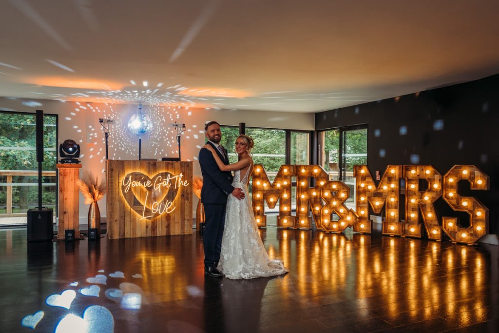 Bride and groom dancing, illuminated 'Mr & Mrs' sign