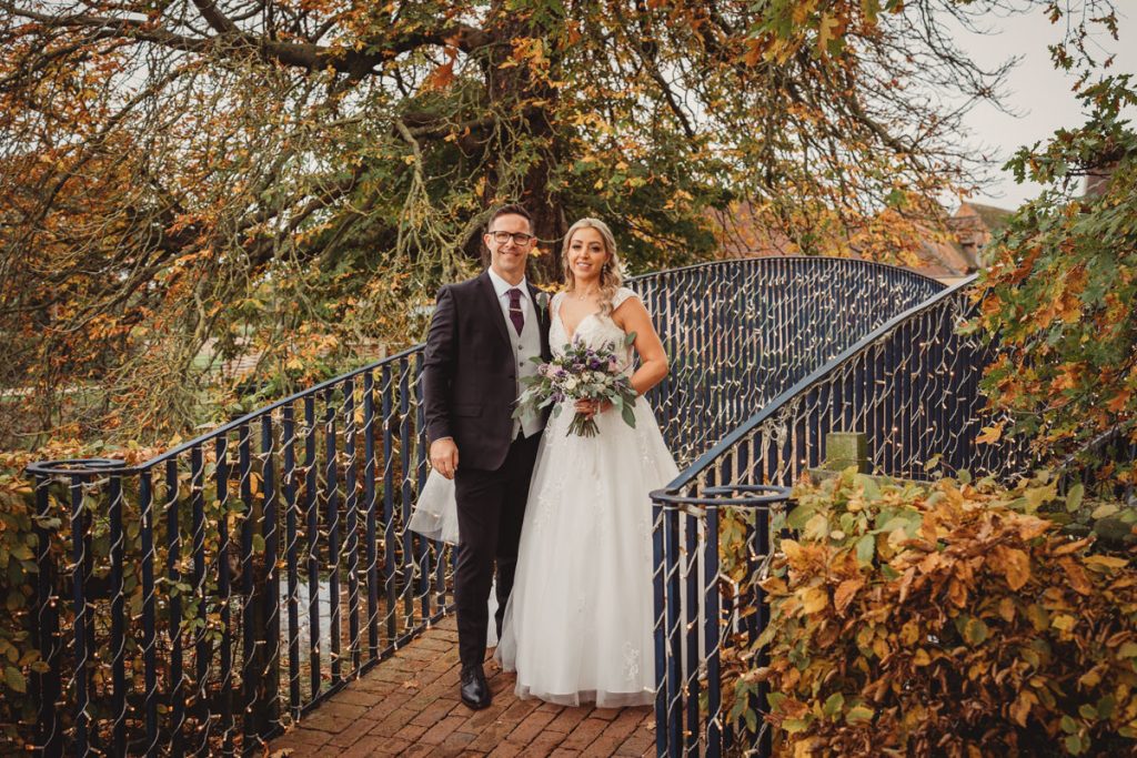 Bride and groom on bridge in autumn setting