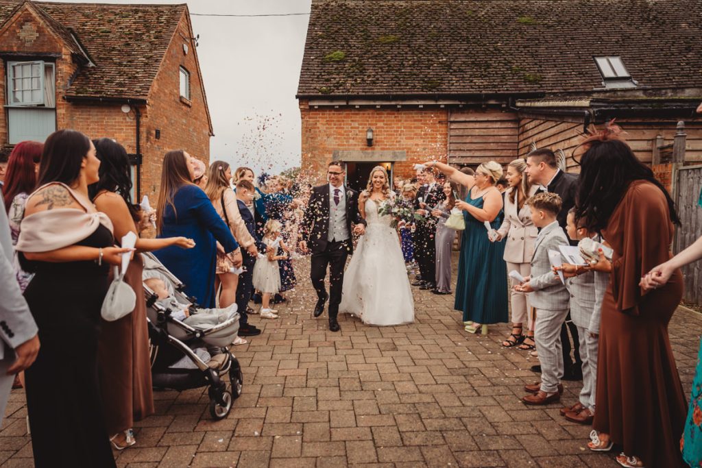 Bride and groom walk through confetti celebration.