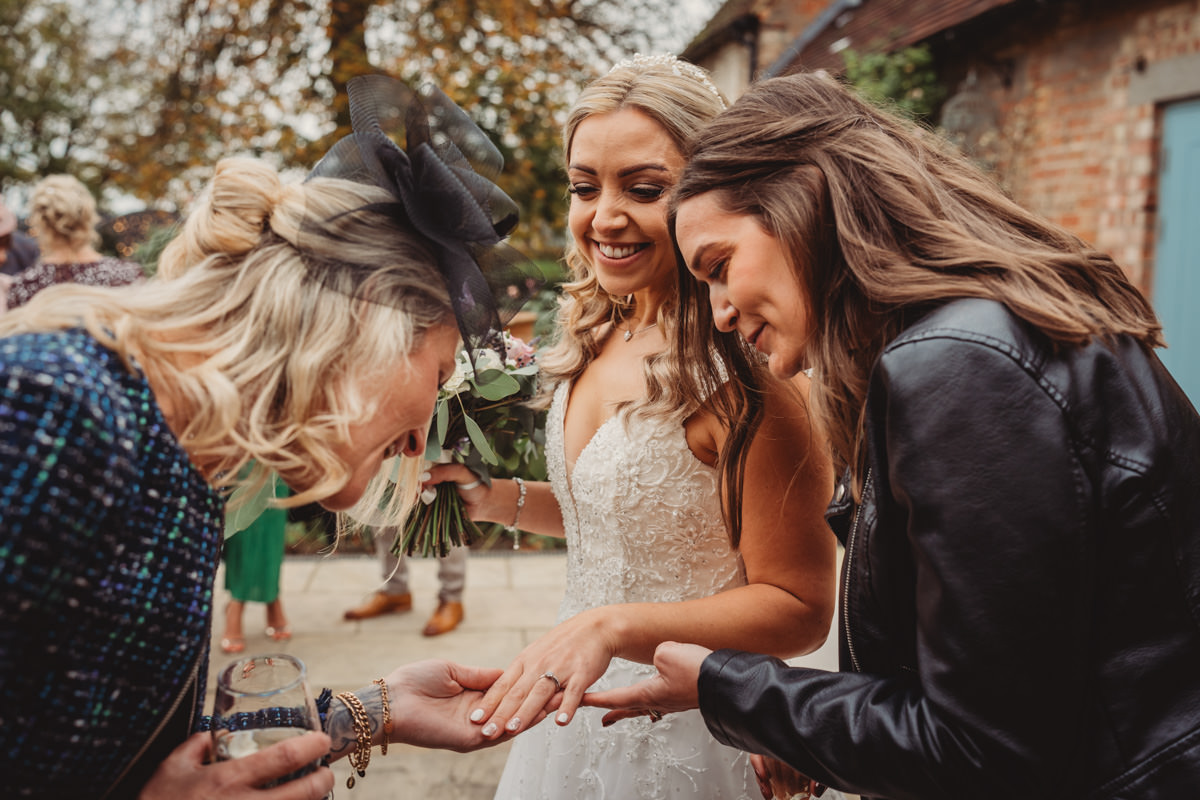 Bride shows wedding ring to friends outdoors