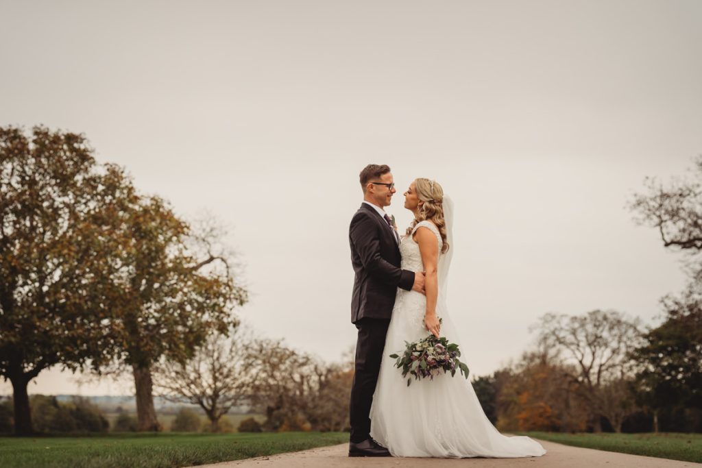 Bride and groom embracing outdoors on wedding day.