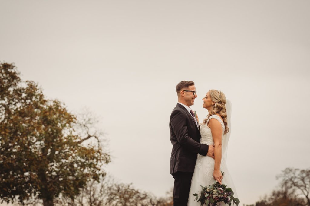 Bride and groom smiling outdoors on wedding day.