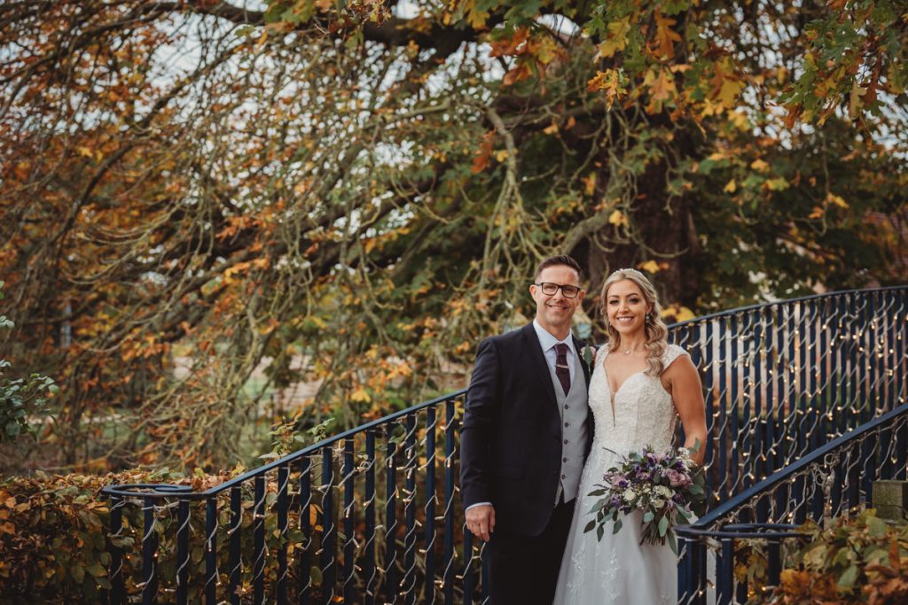 Bride and groom on a bridge in autumn.