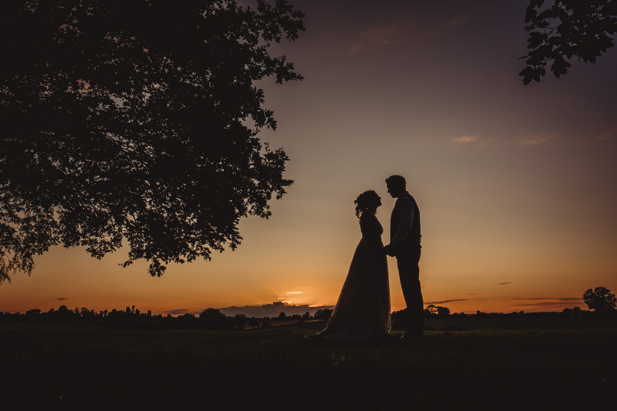 Silhouette of couple at sunset under tree.