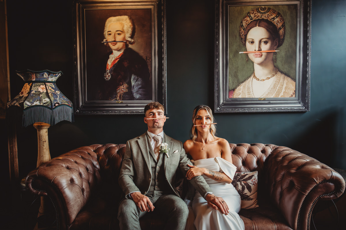 Couple with pencils, humorous art behind them.