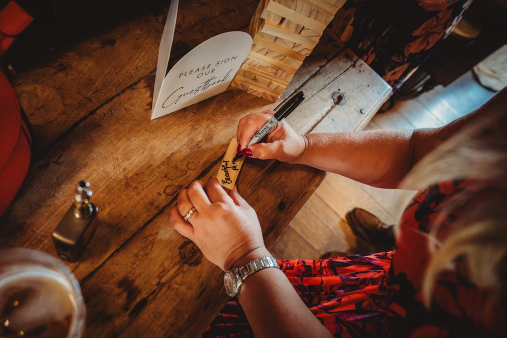 Person signing a wooden guestbook piece.