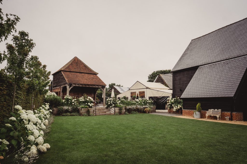 Countryside barn with manicured lawn and flowers.