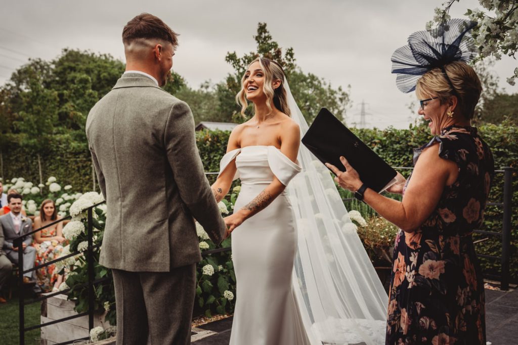 Outdoor wedding ceremony with officiant and couple exchanging vows.