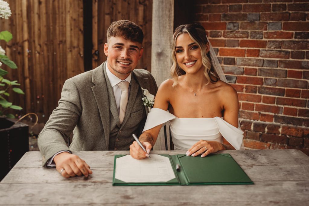 Happy couple signing wedding registry book.