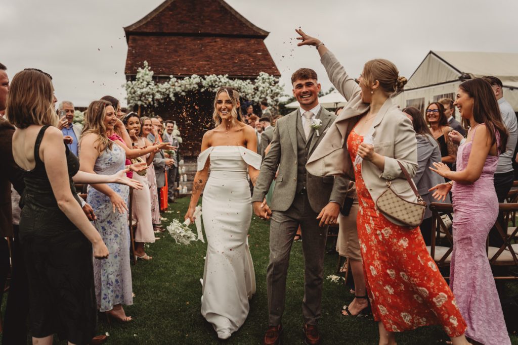 Bride and groom walking through confetti at wedding.