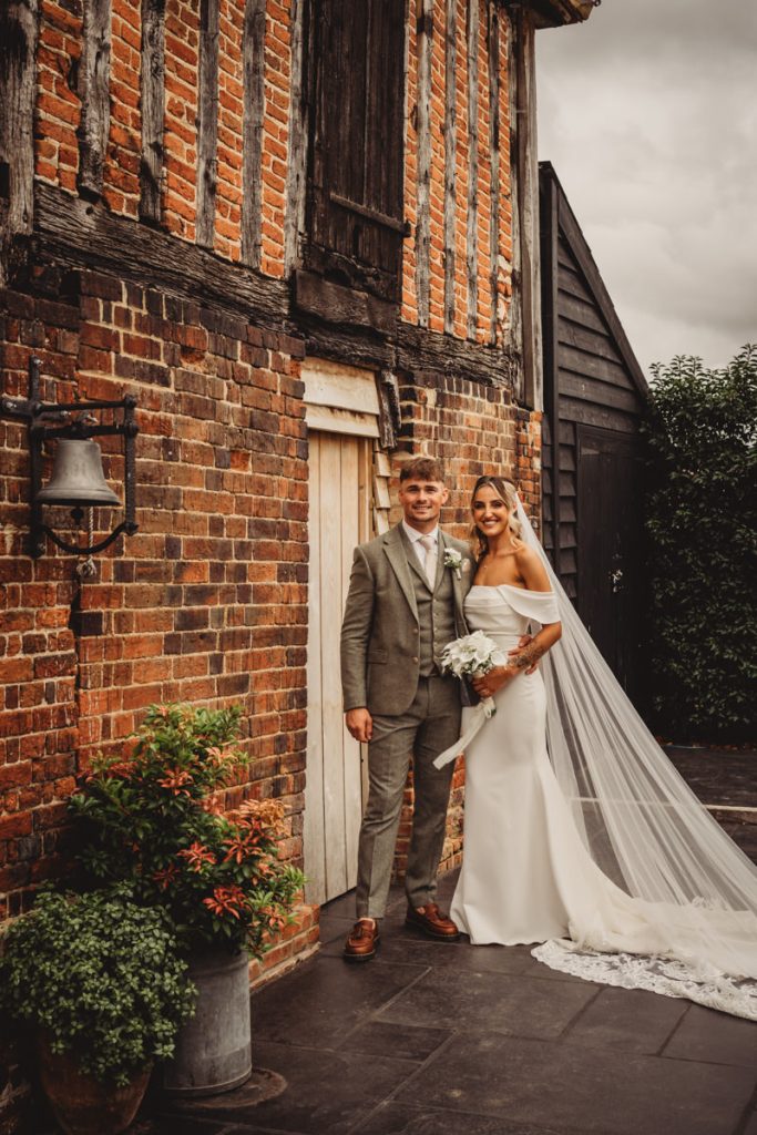 Bride and groom by rustic brick building.