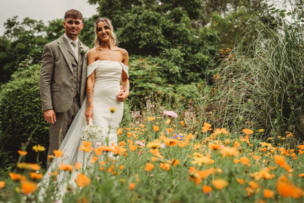Bride and groom in a garden of wildflowers.