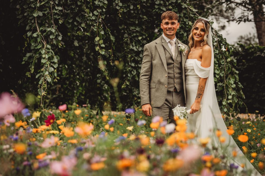 Wedding couple in garden with wildflowers.