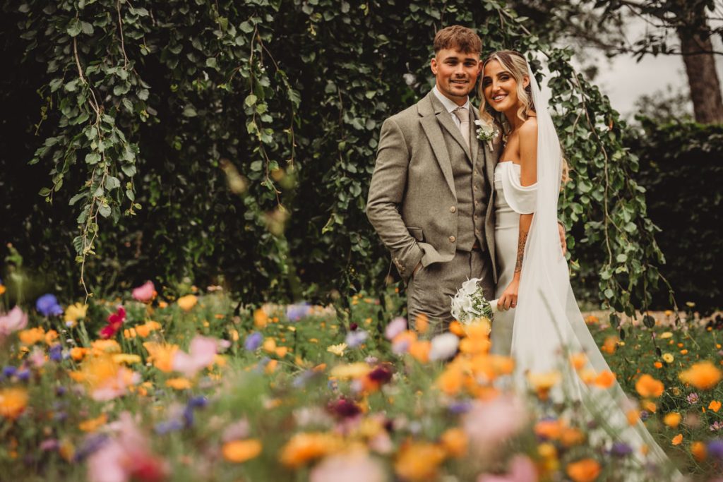 Bride and groom smiling in a floral garden