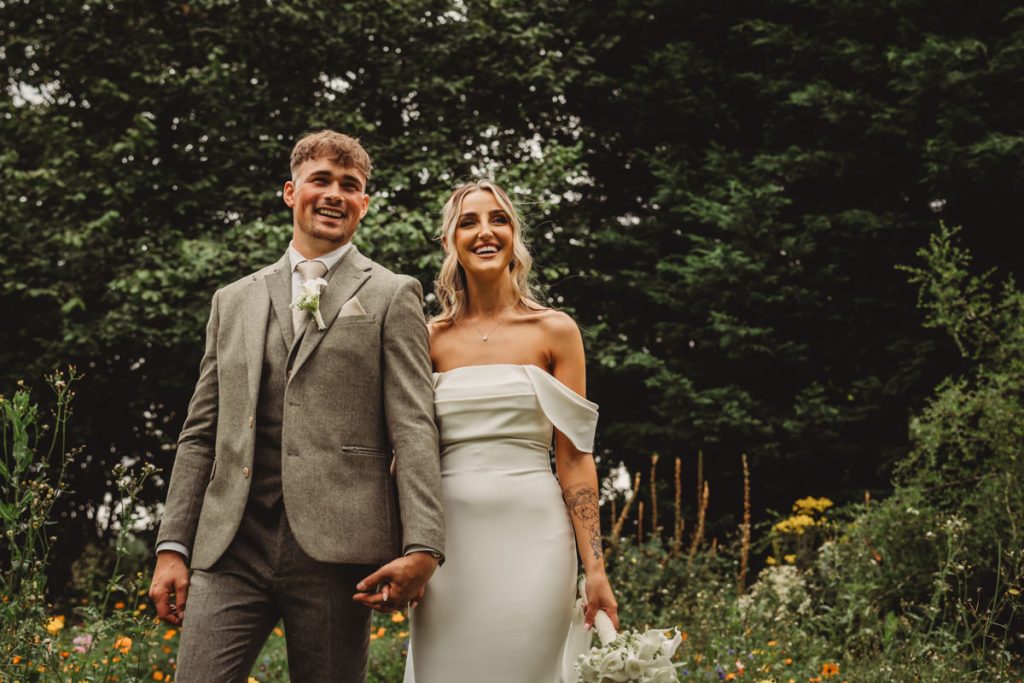 Smiling couple in wedding attire outdoors.