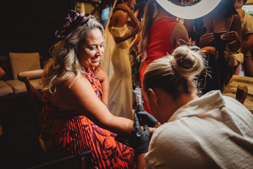 Woman smiling, getting a tattoo at an event.