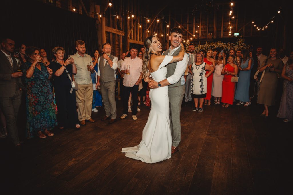 Couple dancing at wedding reception with guests watching.