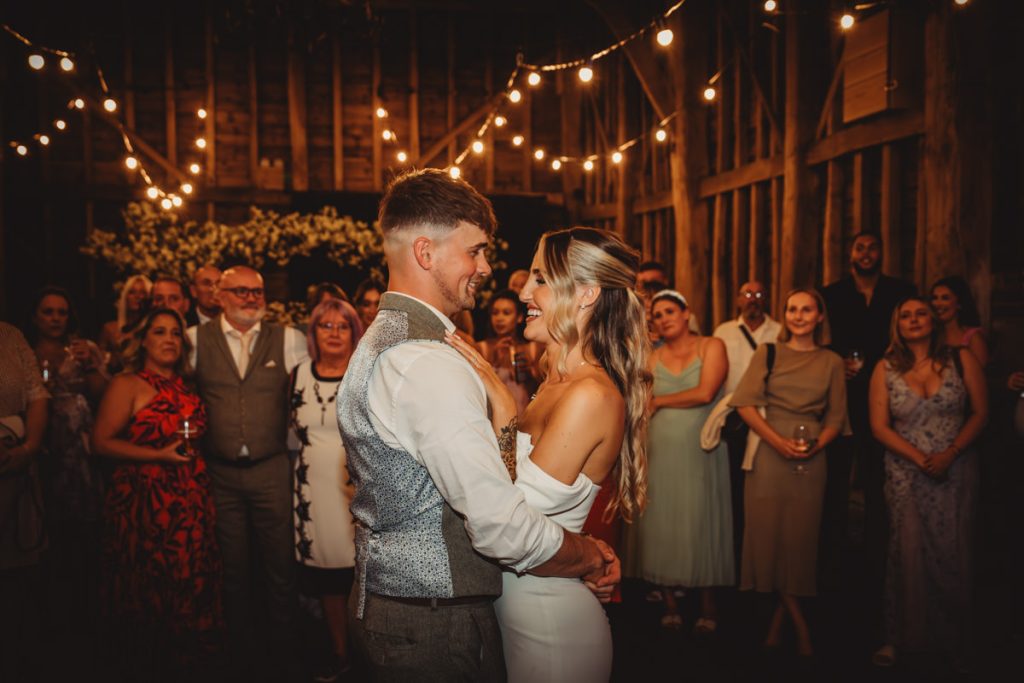 Couple dancing at wedding, surrounded by cheerful guests.