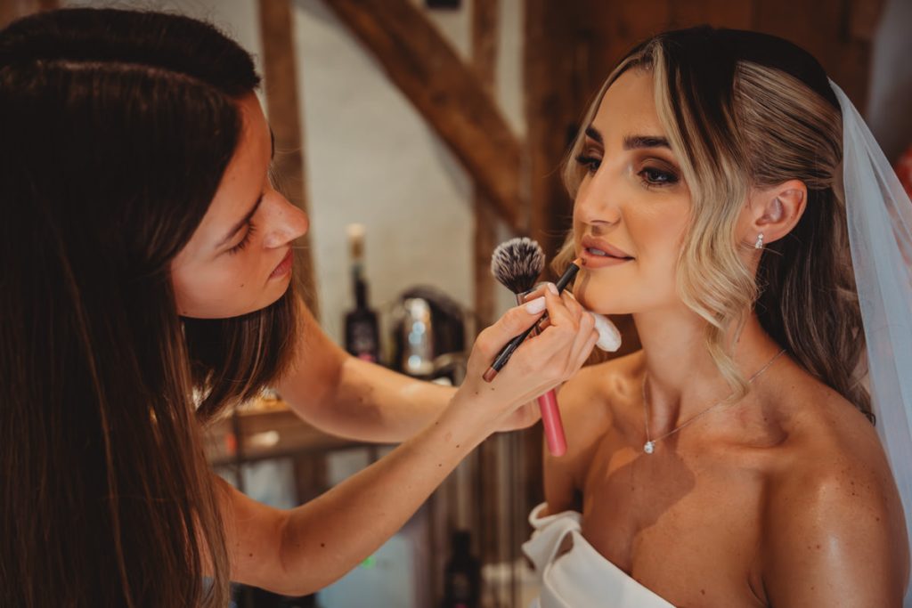 Makeup artist applying lipstick to bride