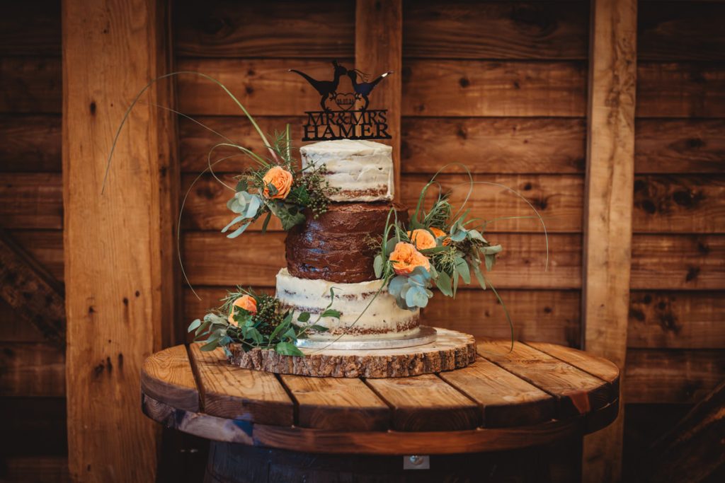 Rustic wedding cake with flowers on wooden table.