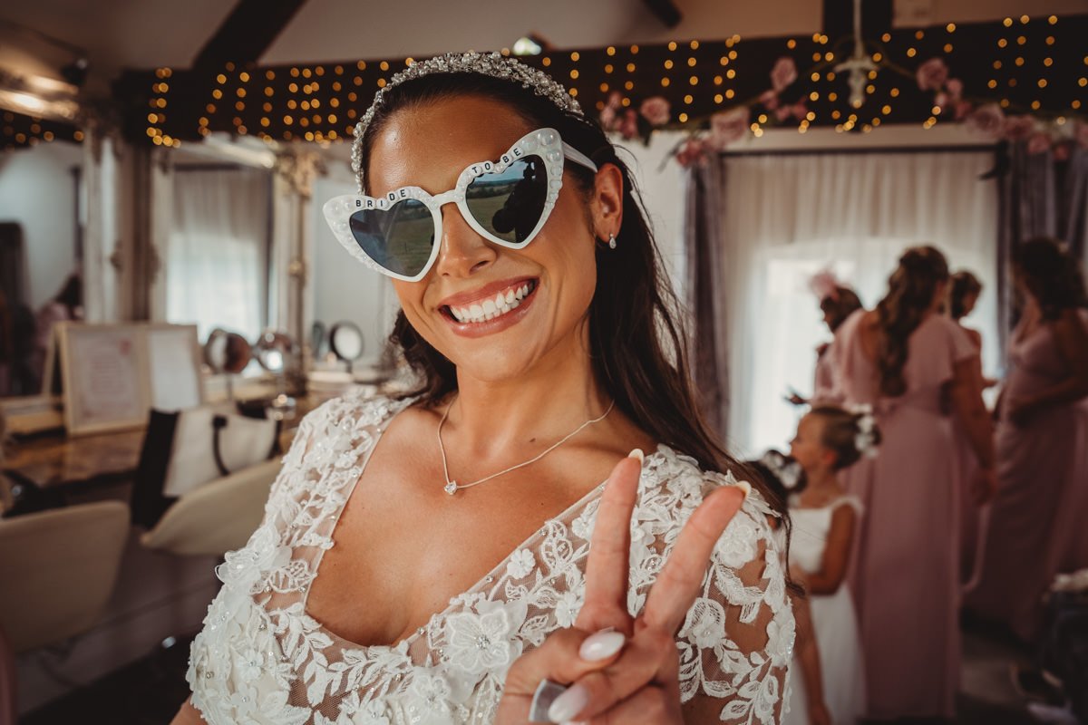 Bride smiling, wearing heart-shaped sunglasses