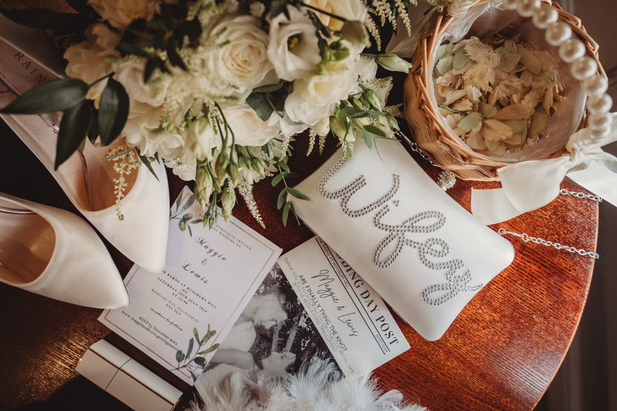 Wedding accessories and invitations on wooden table.
