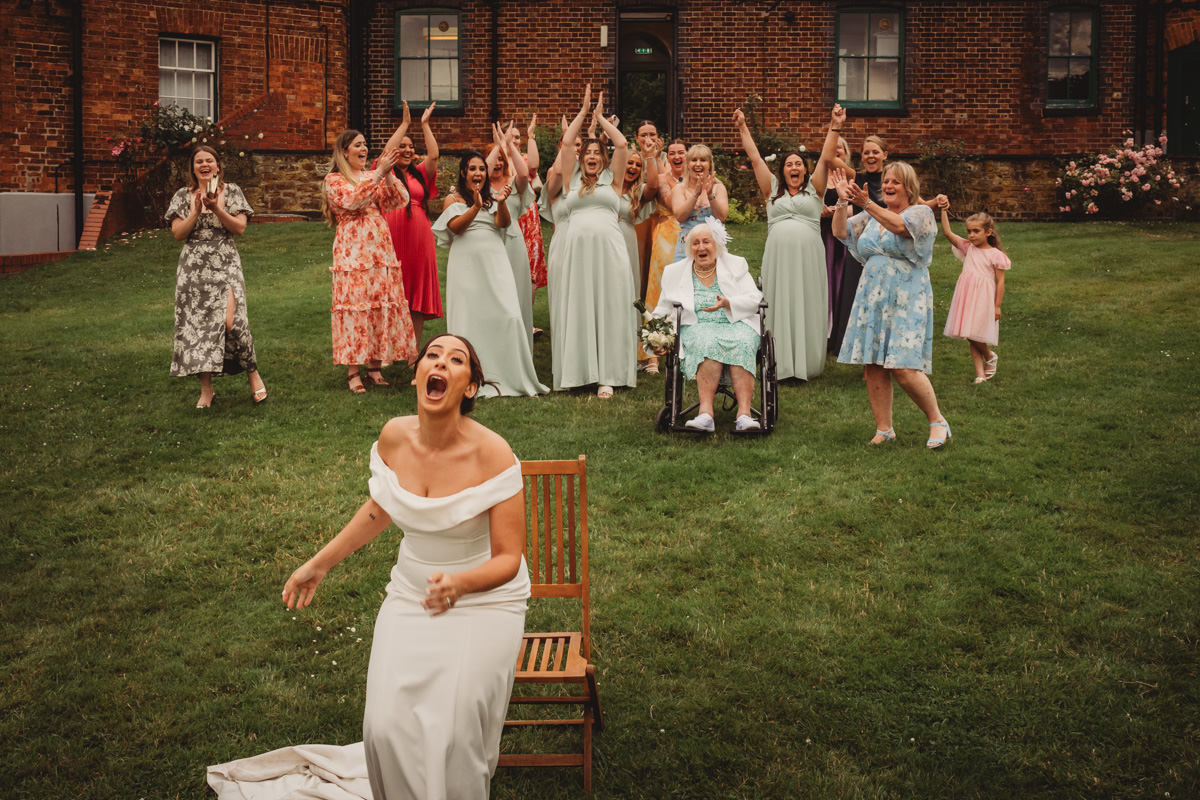 Bride enjoying wedding bouquet toss with bridesmaids cheering