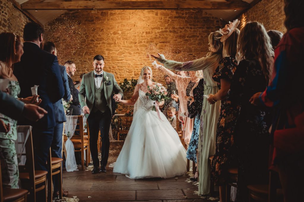 Bride and groom walking through confetti shower.