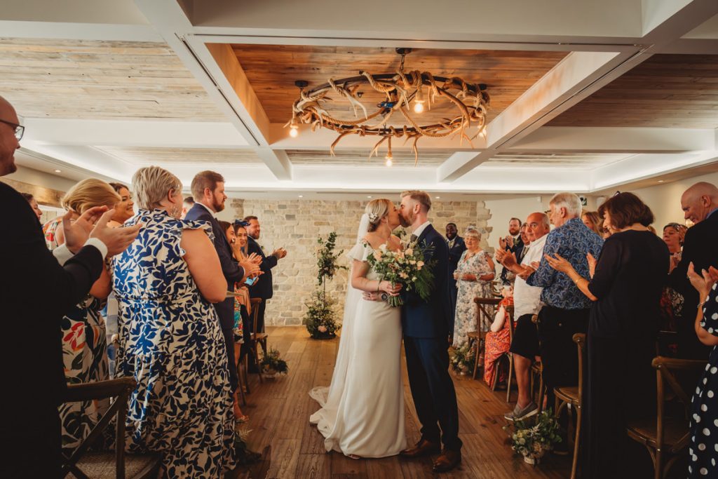 Bride and groom kissing at indoor wedding ceremony.