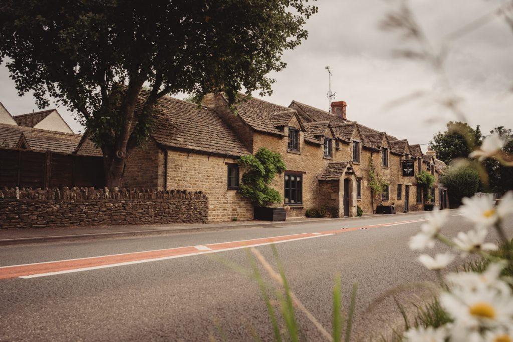 Charming Cotswolds stone cottage beside country road.