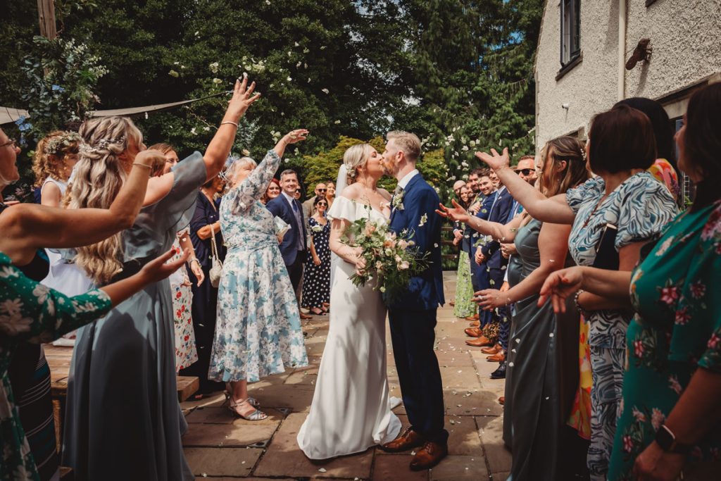 Bride and groom kissing at outdoor wedding ceremony.