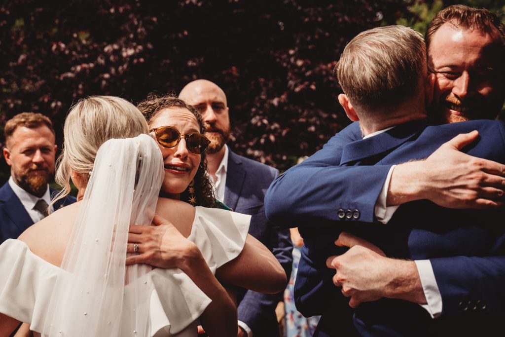 Wedding guests embracing and celebrating outdoors.