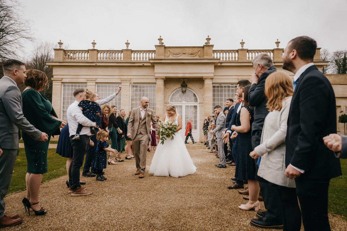 Bride and groom exit ceremony, guests applaud.