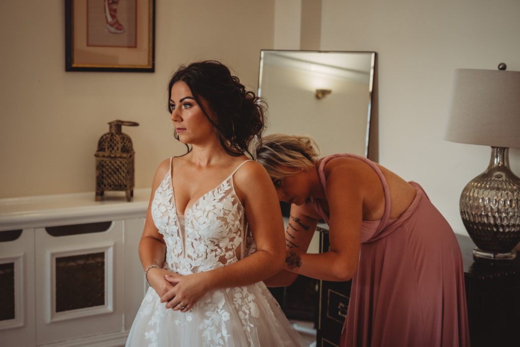 Bride in white dress getting ready with bridesmaid.