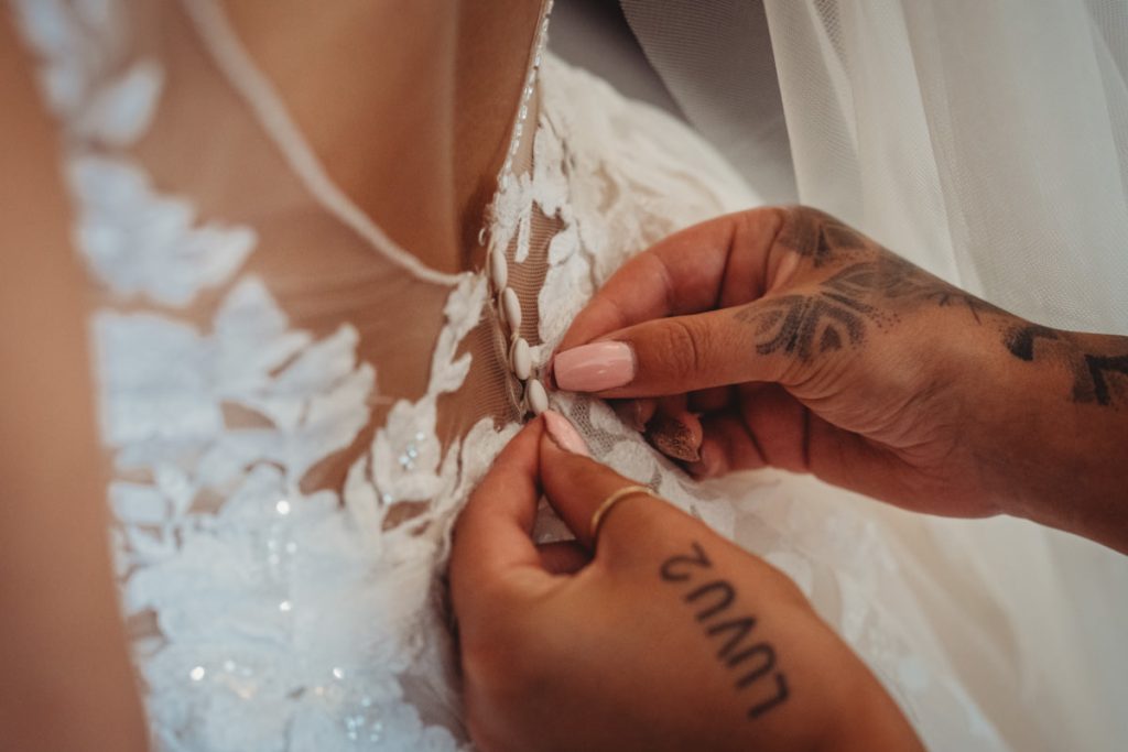 Bridal dress buttons being fastened.