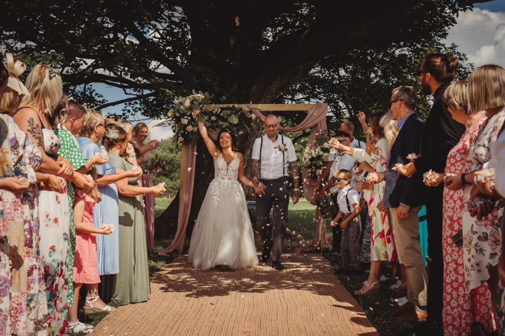 Bride and groom walking down aisle, guests celebrate.