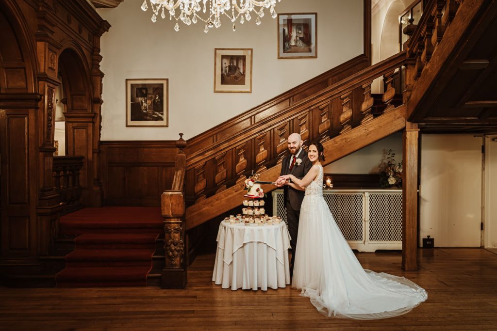 Couple cutting wedding cake in elegant venue.