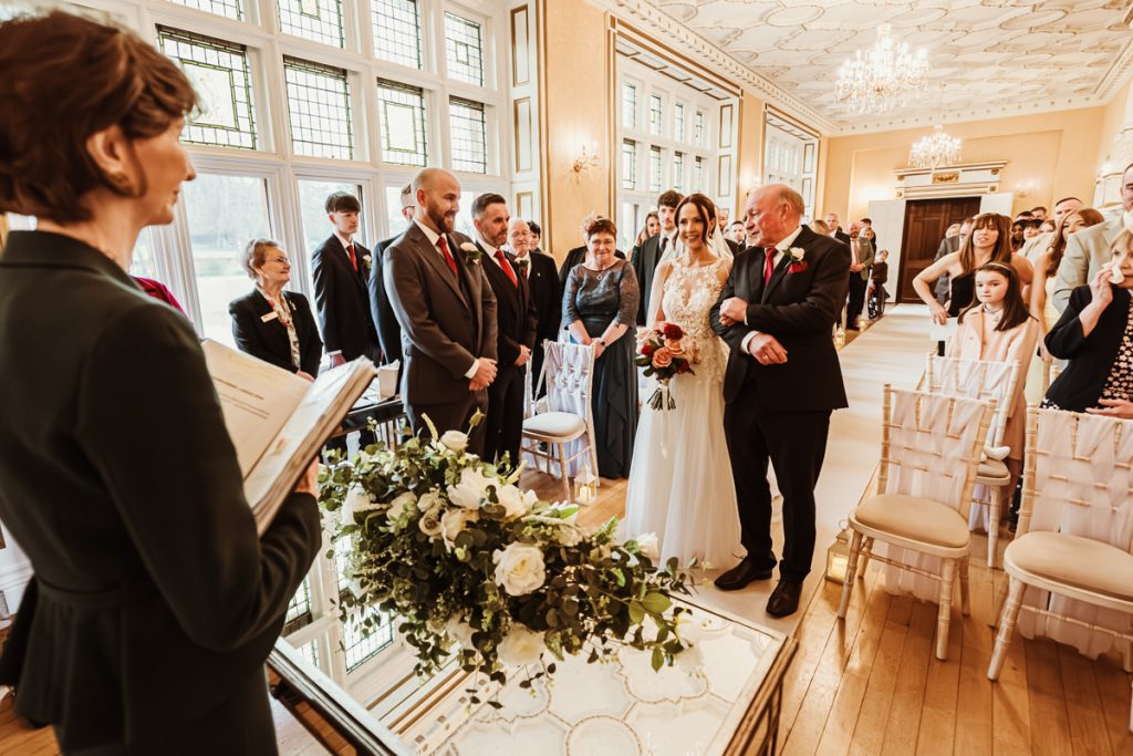 Bride walks down aisle at intimate wedding ceremony.