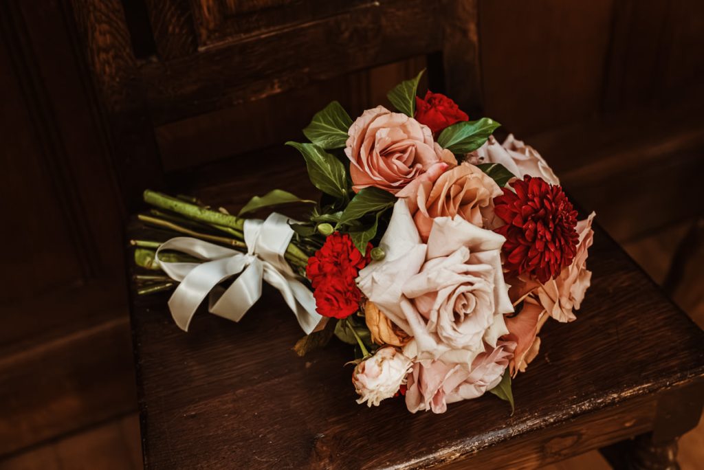 Pink and red flower bouquet on wooden chair.