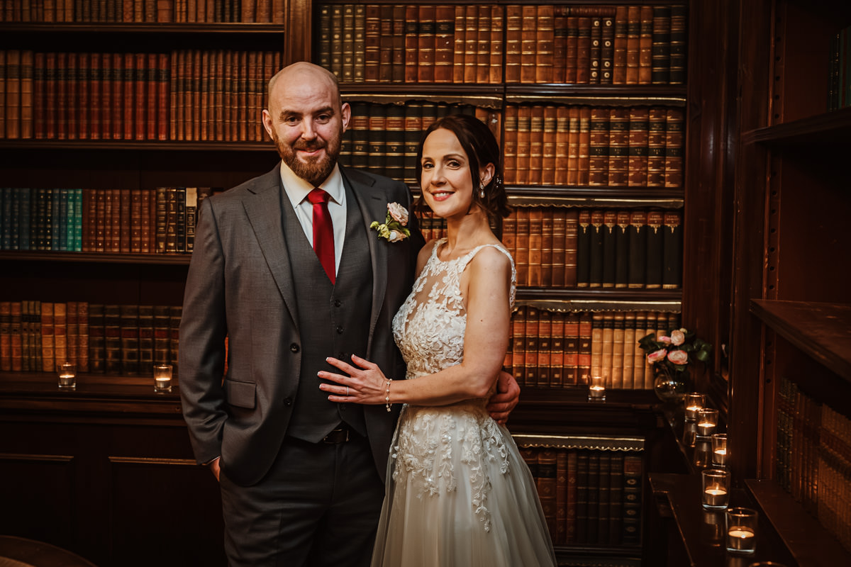 Bride and groom in library backdrop.