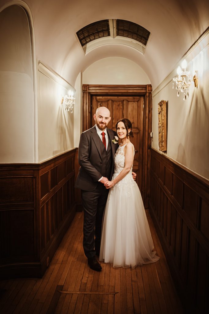 Couple posing in elegant hallway.