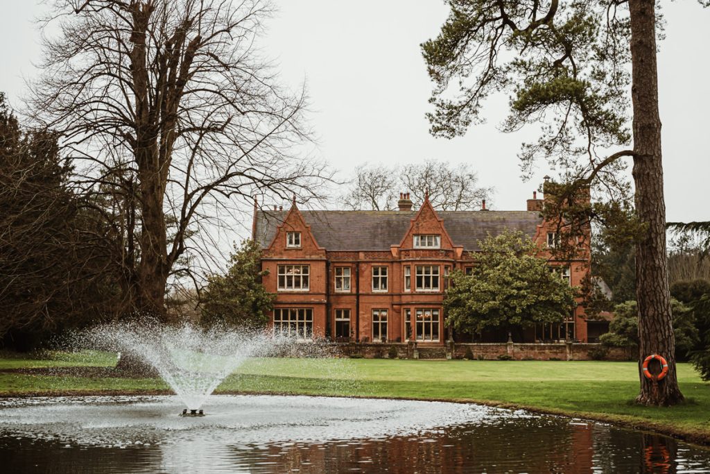 Historic manor house with garden fountain view.