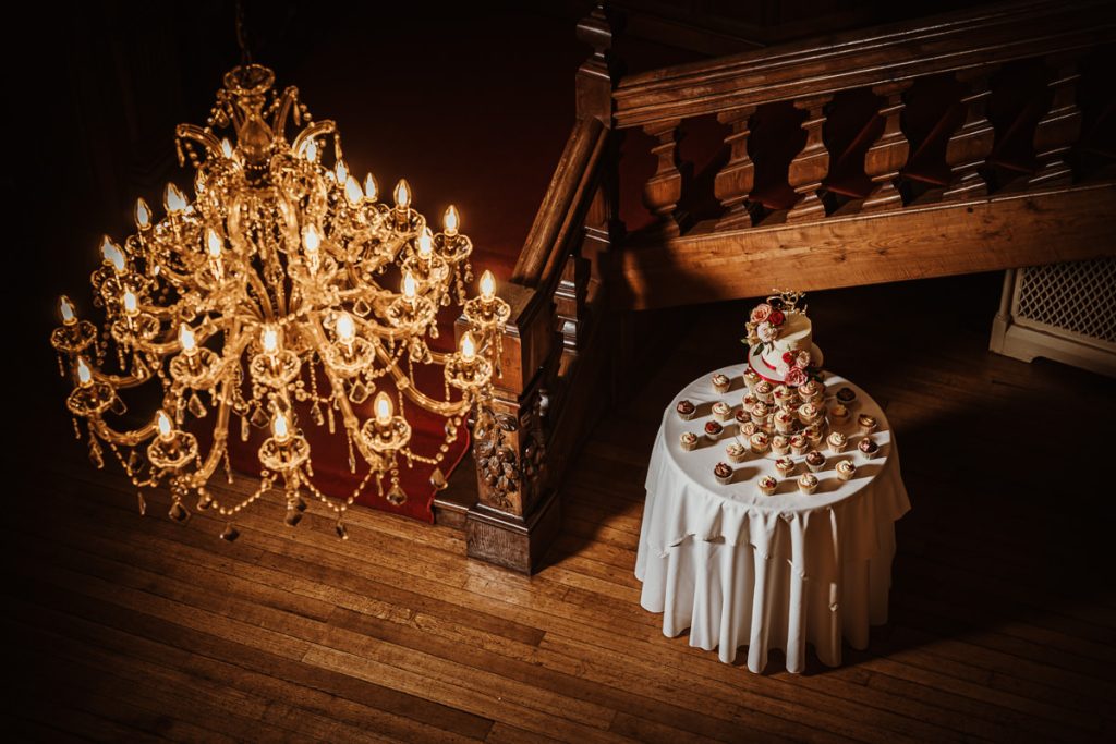 Chandelier above cake table with cupcakes at wedding.