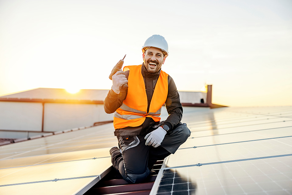 Engineer inspecting rooftop solar panels at sunset.